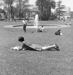 Female student reading on lawn thumbnail