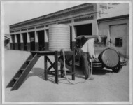 Unknown man pumping gas from a barrel. thumbnail