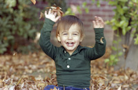 Adam Watkins Sitting in Autumn Leaves Pile at Home thumbnail