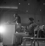 Harry Edwards stands at a podium speaking to a crowd thumbnail