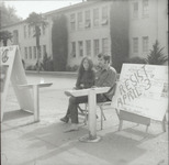 Two students sitting next to draft protest sign thumbnail