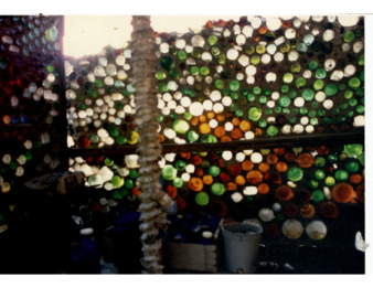 Orange, Red, White, and Green Bottles Embedded in a Structure at Bottle Village thumbnail