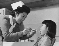 [School nurse administrating throat swabbing to grade school students at Granada incarceration camp] thumbnail