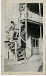 Man climbing exterior staircase, woman looking down from top of stairs. thumbnail