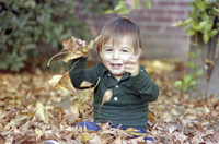 Adam Watkins Sitting in Autumn Leaves Pile at Home thumbnail